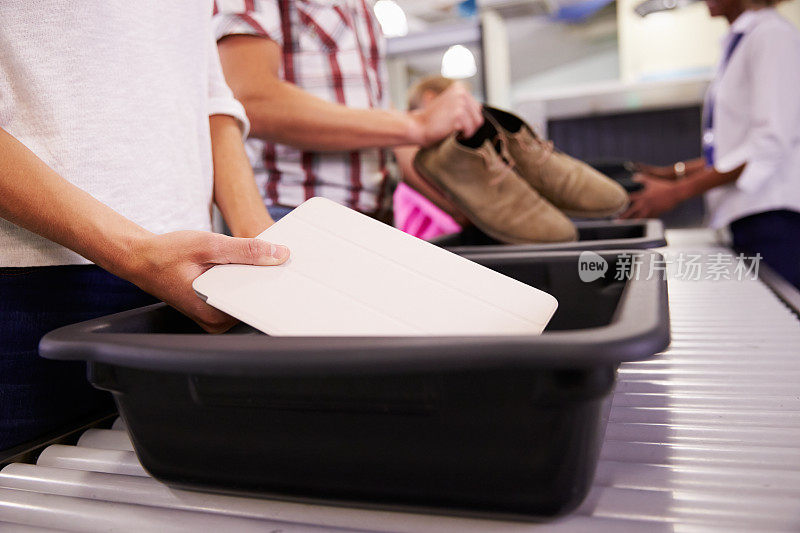 一名男子将平板电脑放入机场安检托盘
