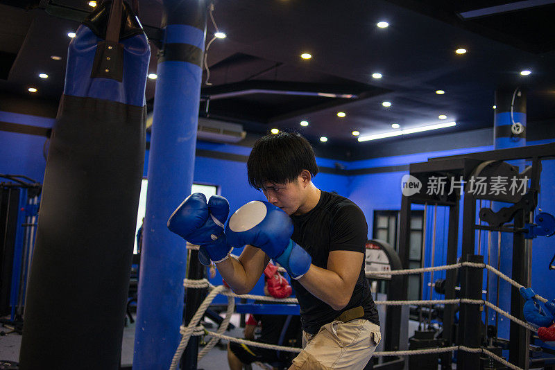 年轻的拳击手准备用蓝色手套打拳击沙袋