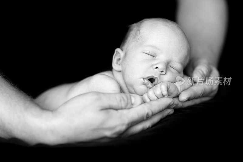 新生儿睡在父亲的手中，孤立，黑人和白人