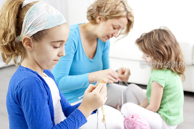 母亲和孩子在家里编织。