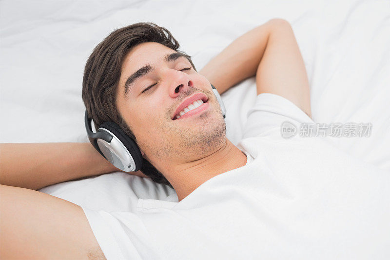 安静的人躺在床上听着音乐，面带微笑
