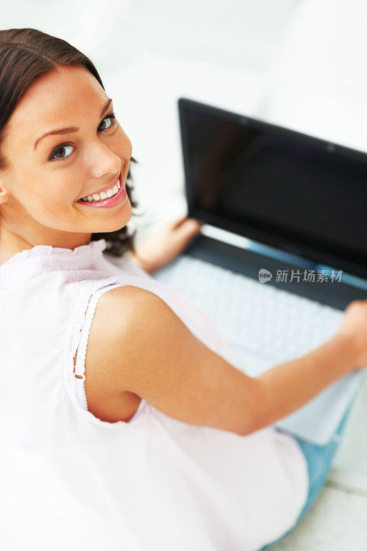 可爱的女士向后看，膝上放着笔记本电脑的肖像