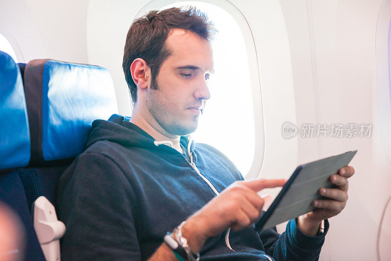 一个拿着平板电脑坐在飞机上的人