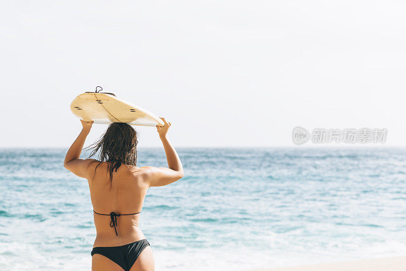 在康沃尔的波斯科诺海滩，一个年轻女子背着冲浪板