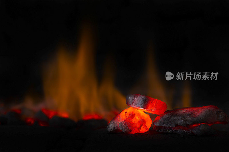 红色的热煤块聚焦在暗色背景与火焰。原煤背景与软焦点排除与颜色和温度。