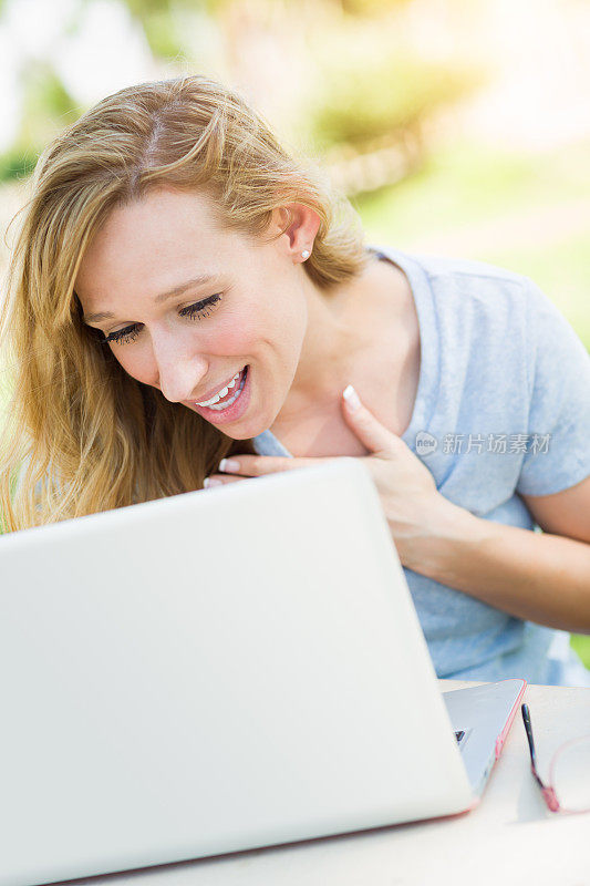 年轻的成年女性在户外用笔记本电脑视频聊天。
