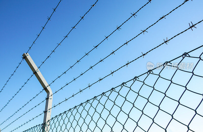 盘绕的剃须刀线和锋利的钢倒钩在铁丝网周围的围栏上，确保安全
