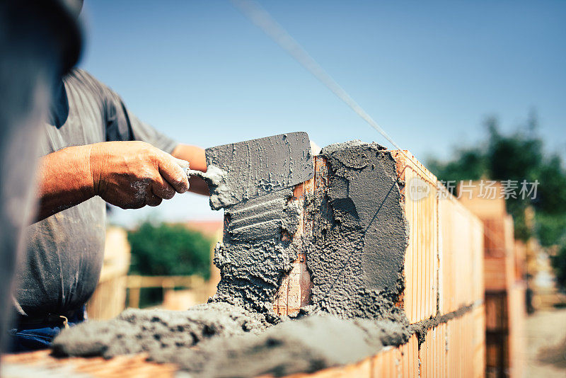砖瓦工建筑工人用泥刀在外墙上安装砖瓦