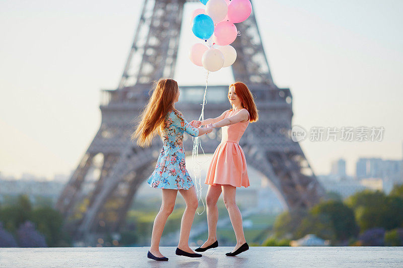 两个女孩在埃菲尔铁塔附近拿着一堆气球