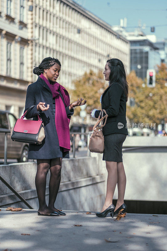 两个中年女商人走在城市里