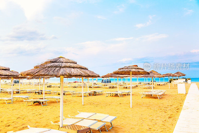 意大利里米尼的沙滩椅和雨伞，在蓝天下的夏日。暑假和放松的概念。