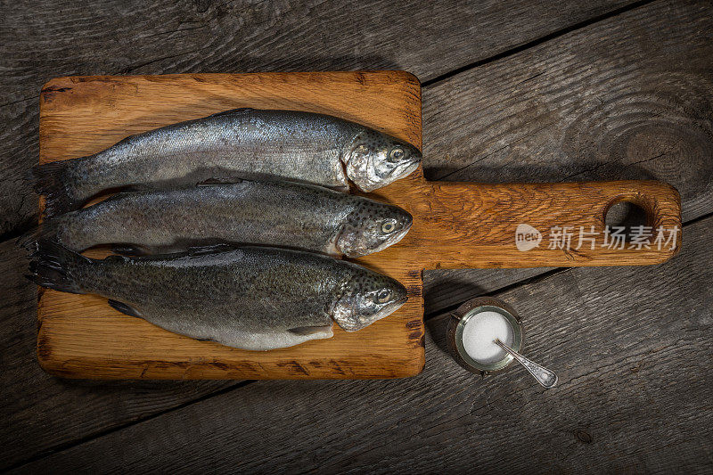 鱼，切菜板上的新鲜鳟鱼，旧的木头背景