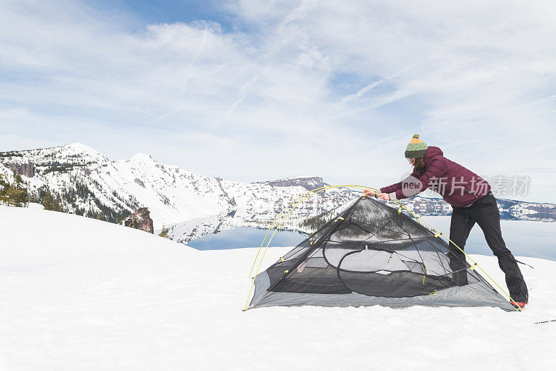 独自的女性徒步旅行者在巨湖的雪地里搭起帐篷