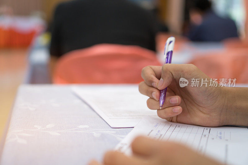 考生在考场内用笔书写报名表。学生坐在教室里学习功课做期末考试。