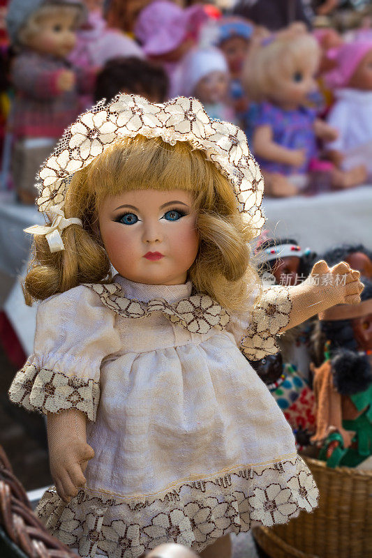 在跳蚤市场上的白色连衣裙上画着眼睛的复古女孩娃娃