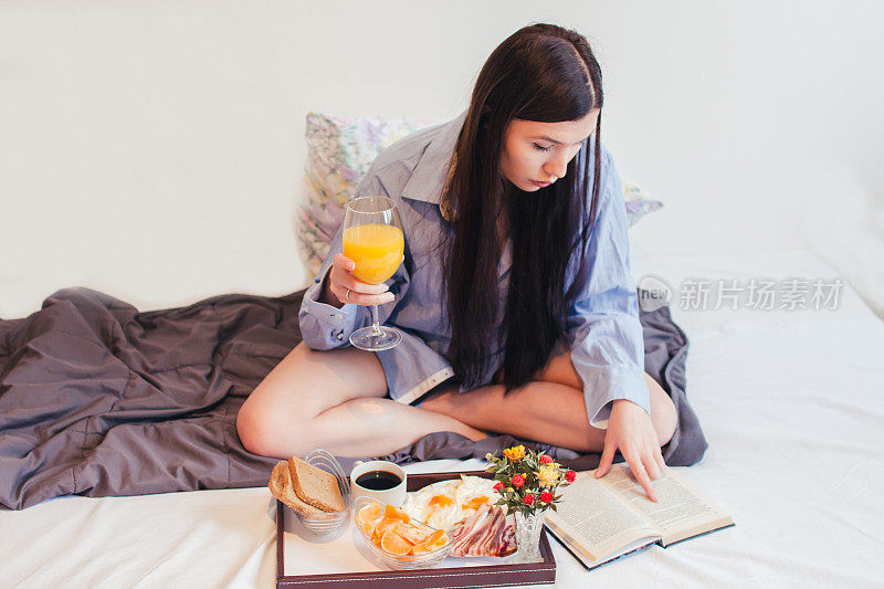 在床上吃早餐，读最喜欢的书的女人。