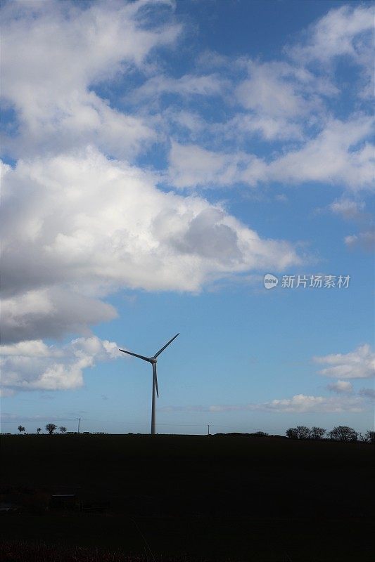 在乡村环境中，蓝天映衬着蓬松的白云，还有风力涡轮机或乡村公路