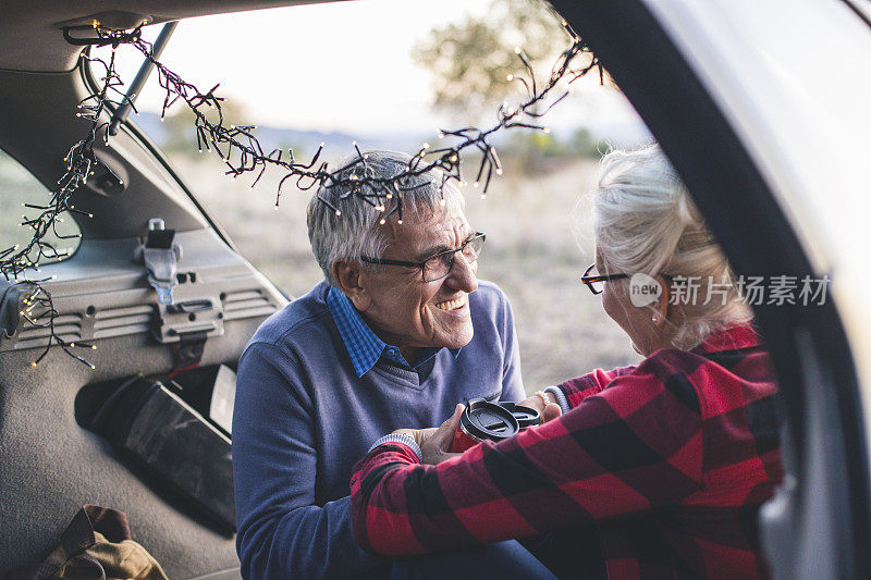 一对老年夫妇在徒步旅行前坐在敞篷汽车后备箱里