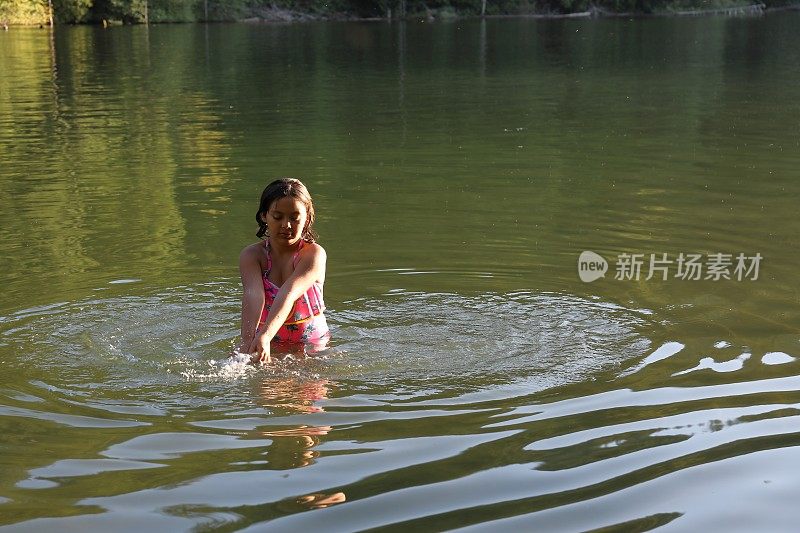 女孩走进淡水湖，在一根圆木上保持平衡