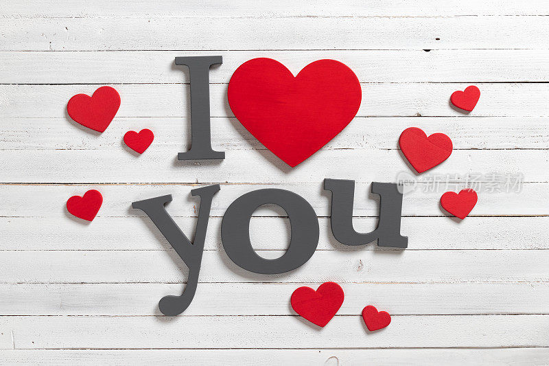 “我爱你”和木制白色背景上的心形。情人节的背景