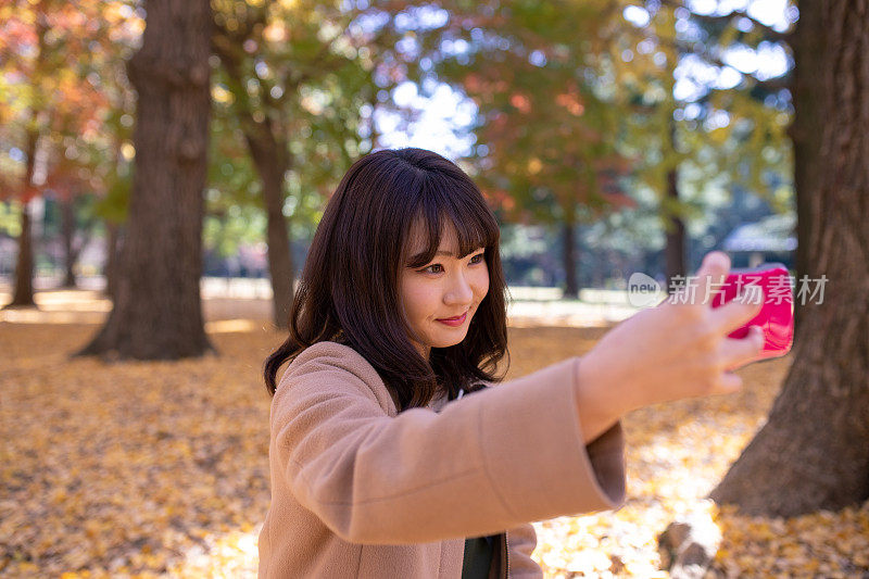 年轻女子在秋天的森林里自拍