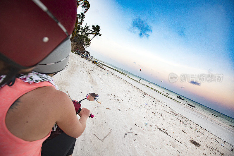 年轻的成年妇女在摩托车上探索热带岛屿的海滩