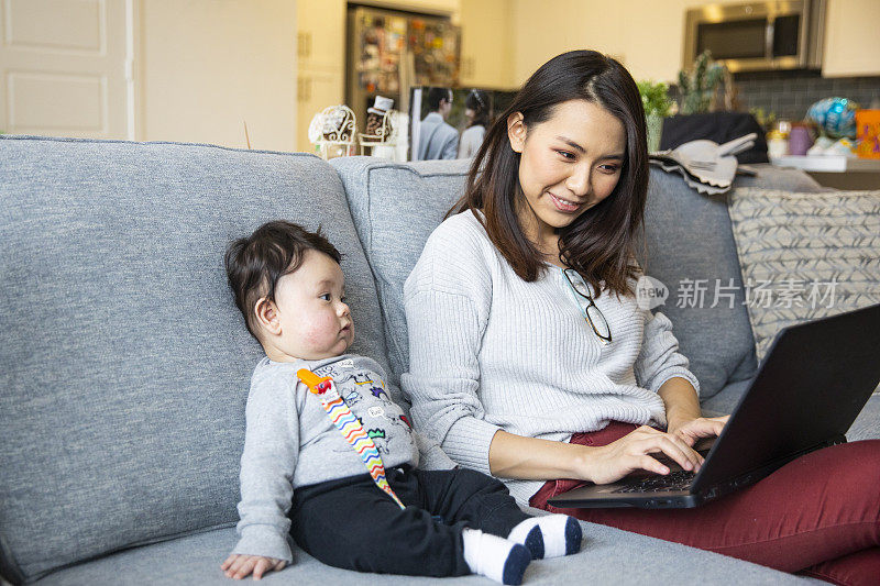 亚洲妇女在家带着孩子工作