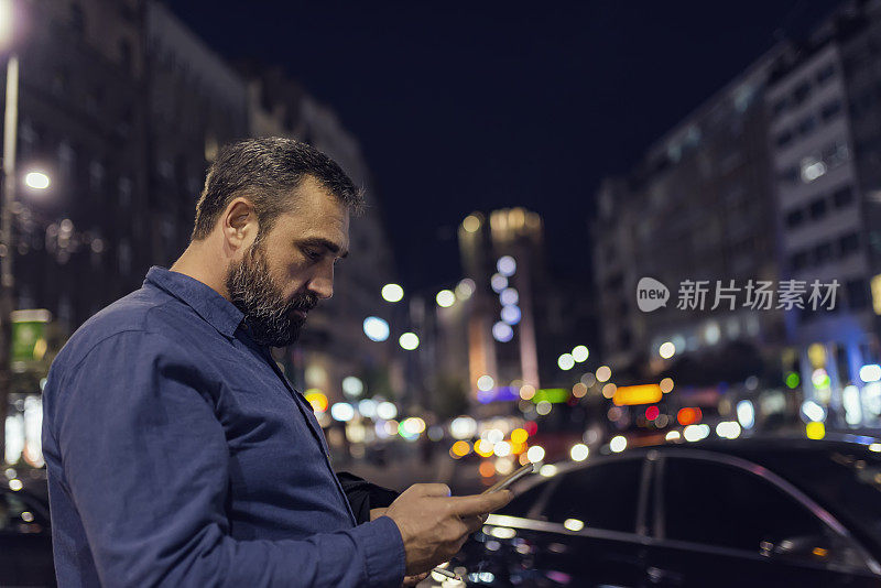 在城市街道上拿着手机的大胡子男人