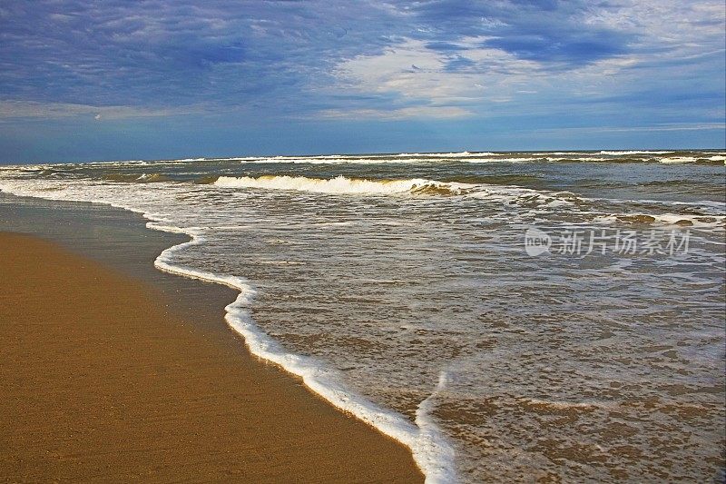 在美国南卡罗来纳，隐蔽的沙滩和海浪在戏剧性的日出