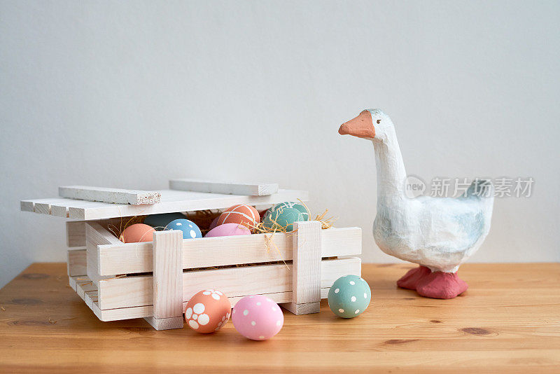 保护复活节彩蛋的可爱鸭仔:玩具鸭放在木箱旁的桌子上