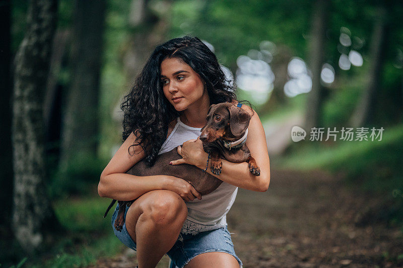 一个年轻女子在公园里牵着她的宠物狗