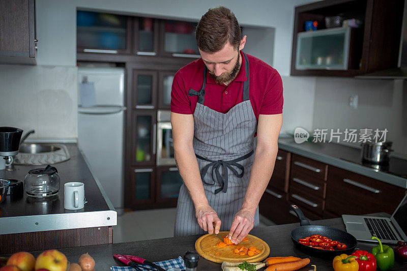 男人在厨房的桌子上切新鲜的春天蔬菜，特写。准备家庭食物，家庭厨房内部。