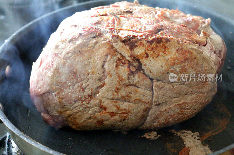 近距离图像蒸，桁架关节的牛肉烤在一个热煎锅和烤箱