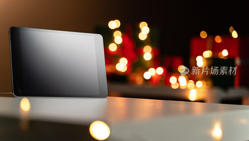 数码平板电脑与空白屏幕前散焦圣诞灯的背景，散焦