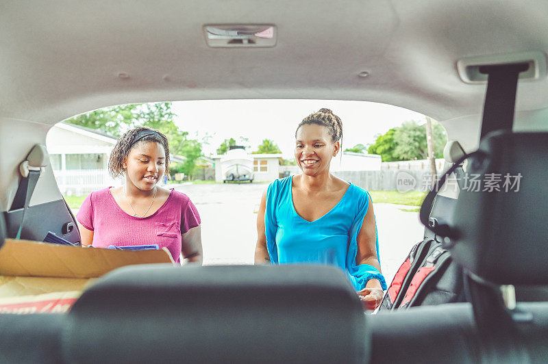 非裔美国母亲和女儿往家里的车上装东西