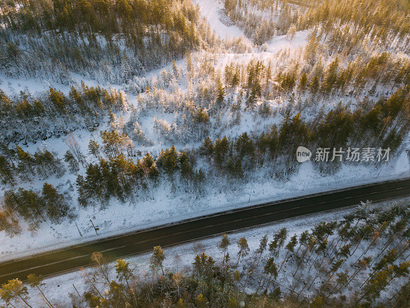 鸟瞰图的道路和森林在冬天的时间。来自空气的自然冬季景观。芬兰的风景从无人机