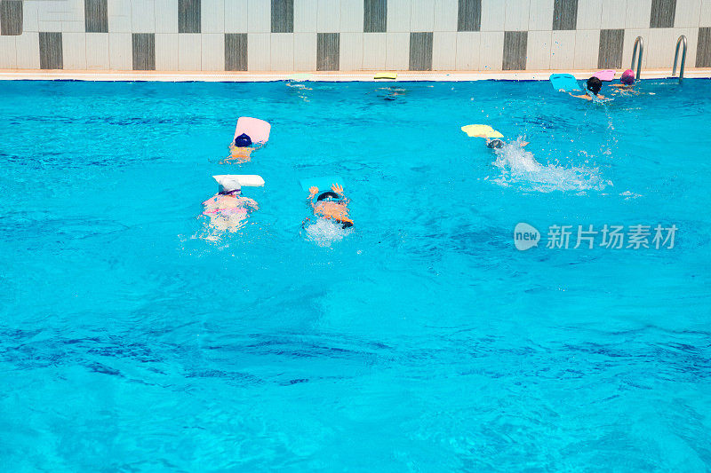 在游泳学校的游泳池里学习游泳的小孩子。儿童或青少年在游泳池进行训练和游泳比赛。