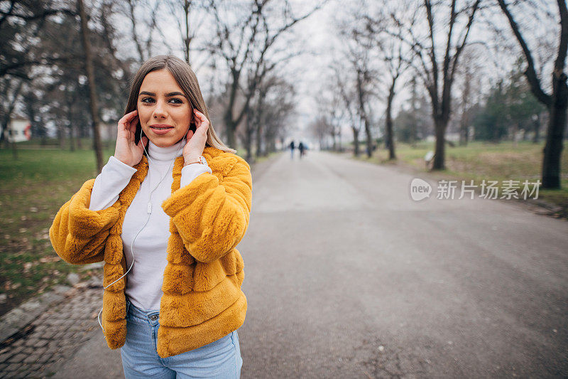 年轻漂亮的女人在公园里听音乐