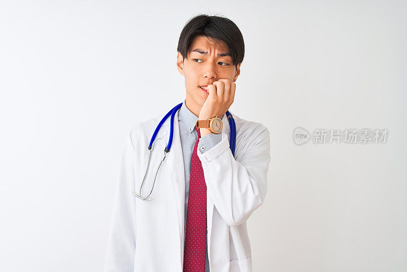 一名中国医生，系着领带，戴着听诊器，背景是孤立的白色，看上去紧张而紧张，双手放在嘴上咬指甲。焦虑的问题。