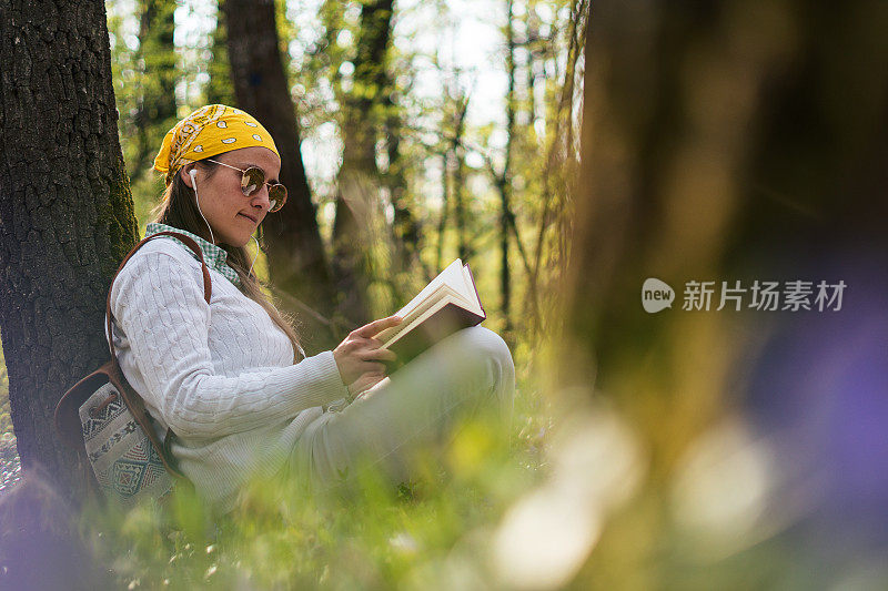 嬉皮女人一边看书，一边在大自然中放松。