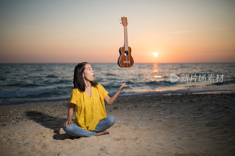 在海滩上拿着悬浮尤克里里的年轻女子