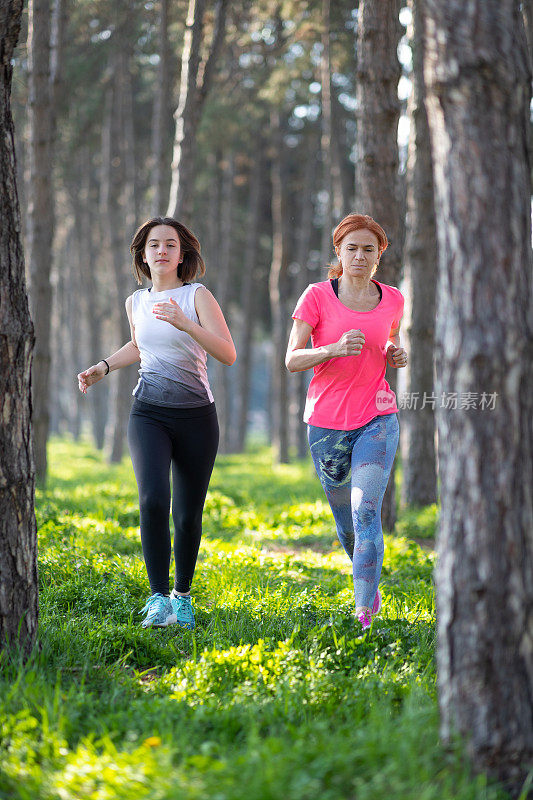 一位中年妇女和她十几岁的女儿在树林里慢跑