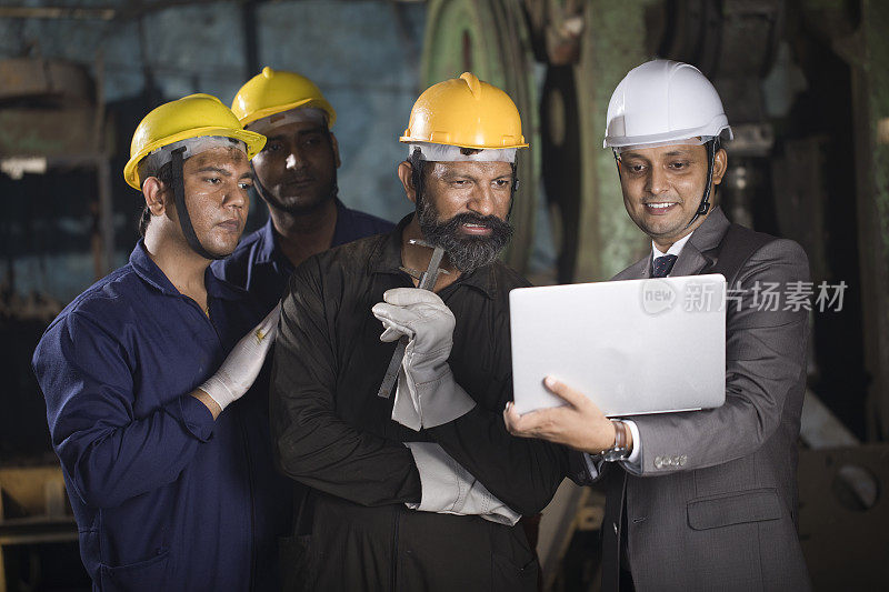 机械师与工程师在工厂使用笔记本电脑进行讨论