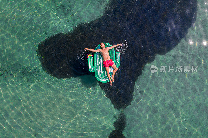 鸟瞰图上的人浮动在湖上与充气仙人掌日光浴