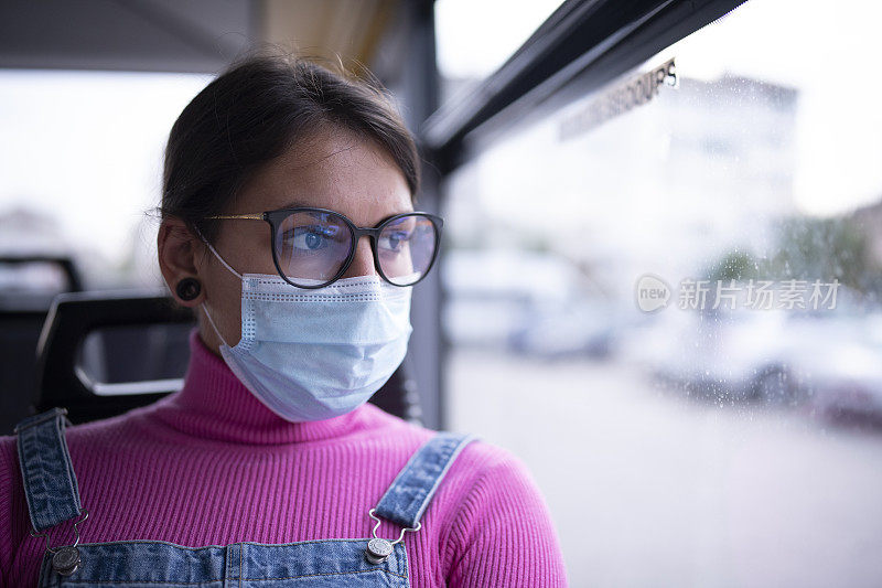 一位戴着防护面罩乘坐公共交通工具的年轻女性的肖像。