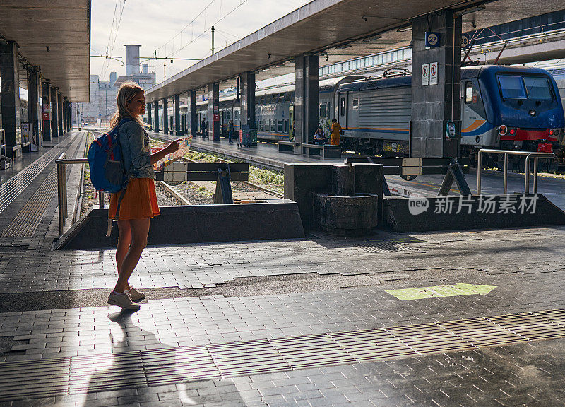 年轻的女游客在等火车时看地图