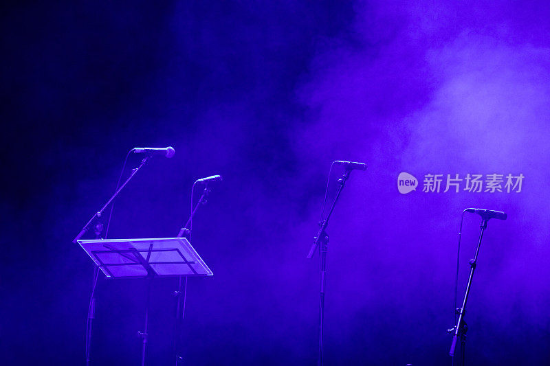 音乐会前舞台上的麦克风。紫色灯光的黑暗舞台