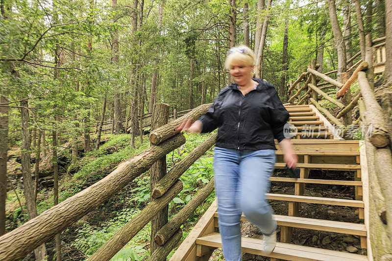 生态步道自然地标在波科诺斯山脉，宾夕法尼亚州。在宾夕法尼亚州的布什基尔瀑布，一名心不在焉的妇女走下树林的台阶