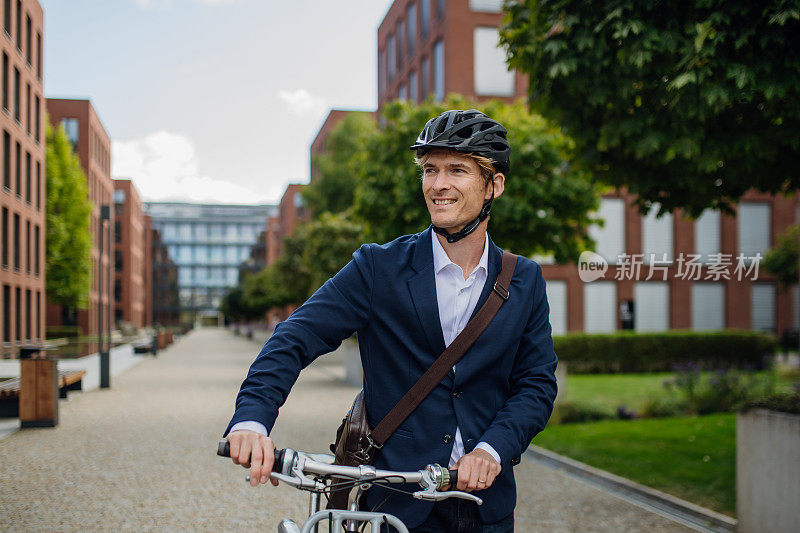 英俊的中年男子穿着西装骑着自行车在城市里穿梭。在漫长的工作日后骑自行车下班的男性城市通勤者。