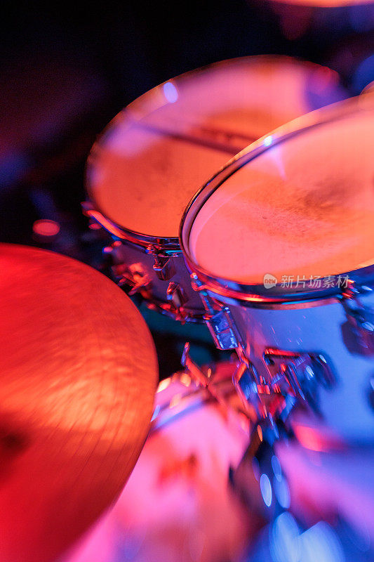 舞台上鼓套件的特写与充满活力的红色灯光-现场音乐表演设备